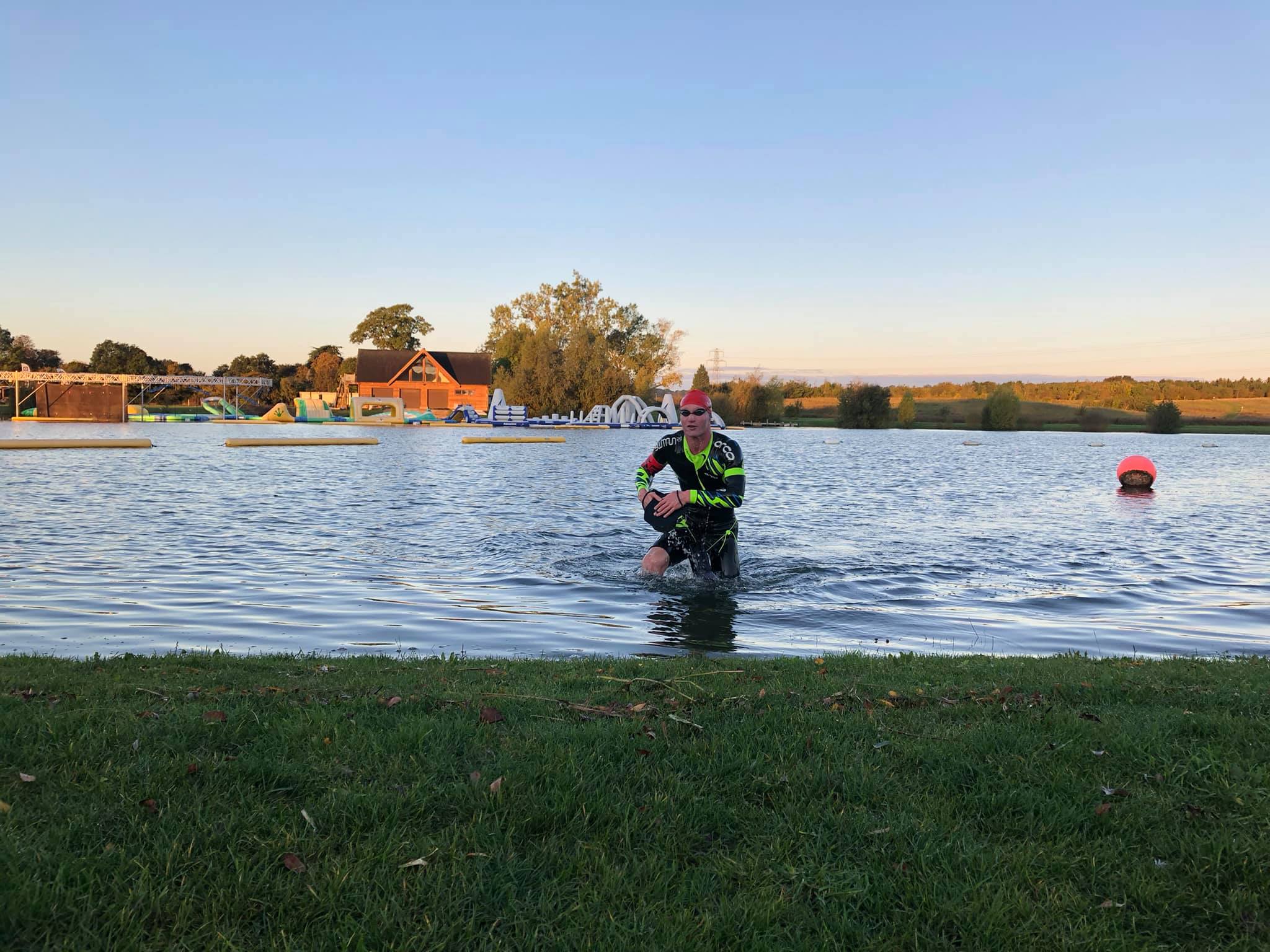 swimrunner exiting the water wearing a green swim cap. swimrunner exiting the water wearing a green swim cap.