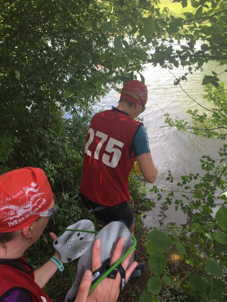 swimrunners about to enter water through trees