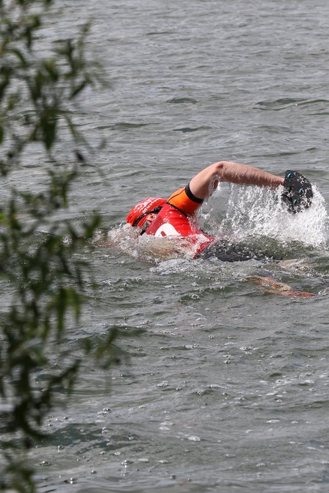man in an orange vest swimming in a grey river man in an orange vest swimming in a grey river