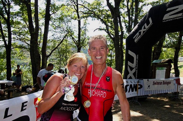 Two swimrun competitors holding their medals at the finish line.