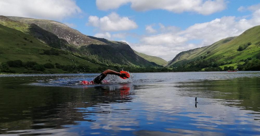 swimmer with orange paddles in a mountain lake landscape swimmer with orange paddles in a mountain lake landscape