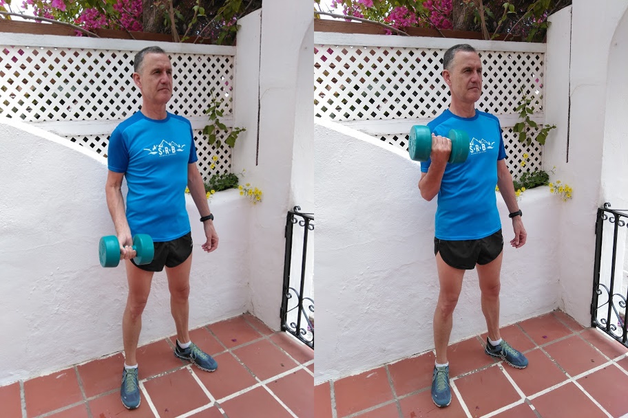 A man in a blue top demonstrating a bicep curl exercise.
