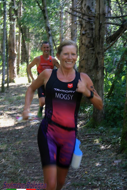 Two swimrun competitors running through a forst, wearing triathlon suits at the Swimrun Bologna event