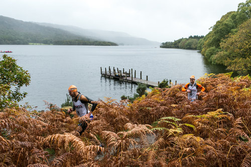 A view over a lake with a wooden jetty in the distance, and brown bracken in the foreground