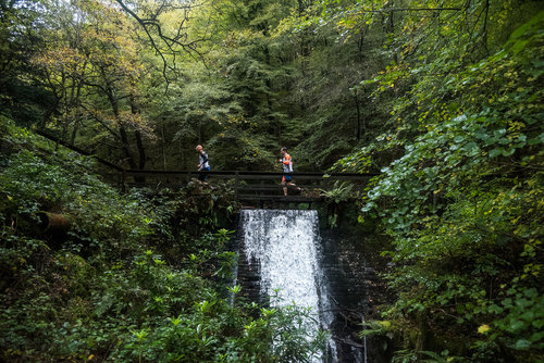 Swimrunners running across a bridge at a Breca Swimrun event.