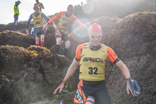 Swimrun racers making their way downhill through boulders, towards the camera.