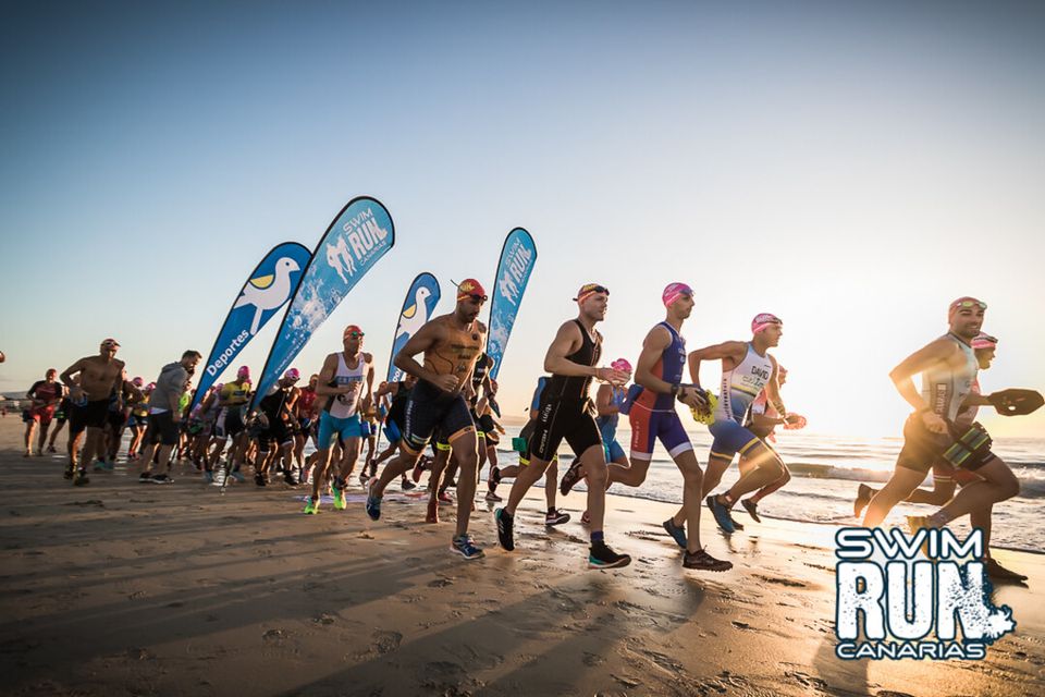 Swimrun competitors running on sand in the Canary Islands swimrun event. Swimrun competitors running on sand in the Canary Islands swimrun event.