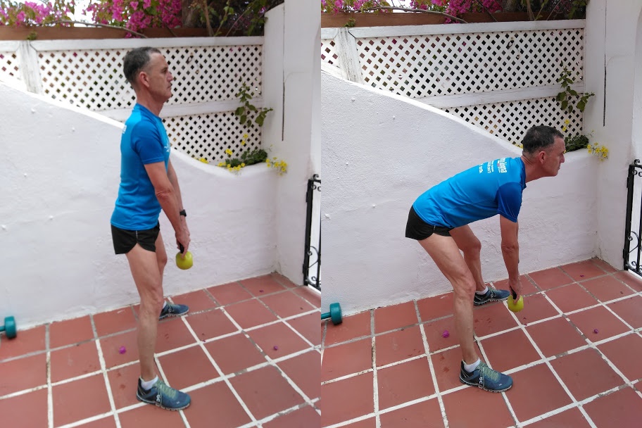 A man in a blue top demonstrating a kettle bell exercise.