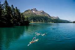swimmers in lake by mountains