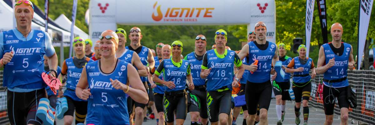 A group of swimrunners wearing blue tops running at the start of an IGNITE swimrun event. A group of swimrunners wearing blue tops running at the start of an IGNITE swimrun event.