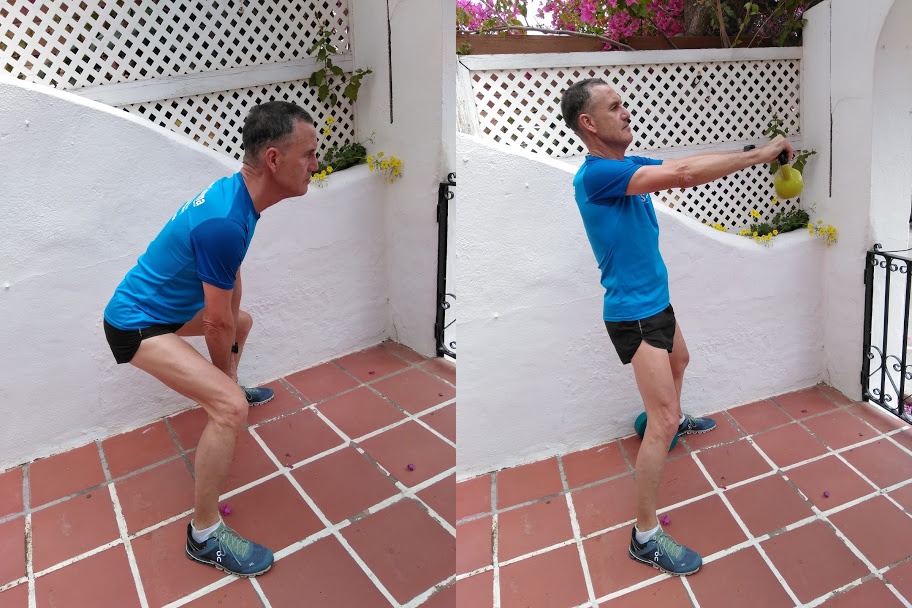 A man in a blue top demonstrating a kettle bell weight exercise.