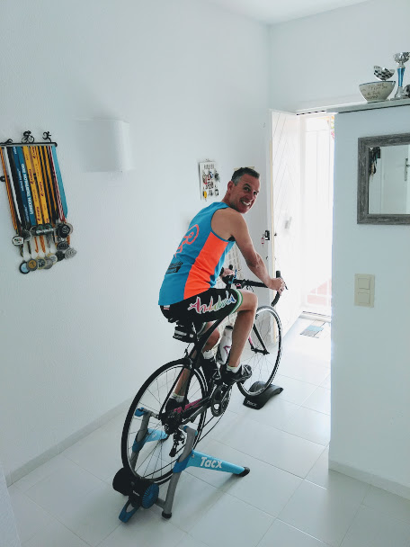 A man in a blue and orange top exercising on an indoor bike.