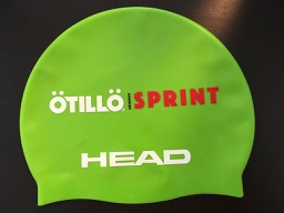 A green Otillo SwimRun Sprint swim cap resting on a wooden surface A green Otillo SwimRun Sprint swim cap resting on a wooden surface