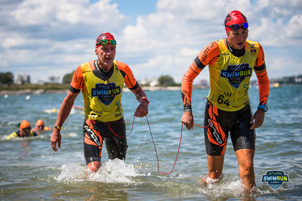 Two swimrun competitors wading out of water at the end of a swim leg